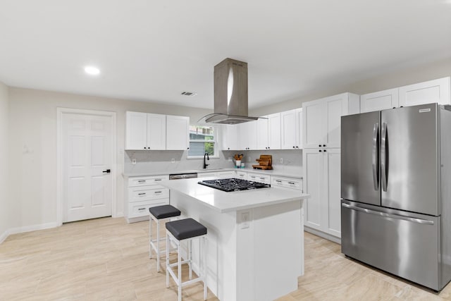 3915 Southmore Cir, Houston, TX 77004 - kitchen with stainless steel appliances, island range hood, a kitchen island, white cabinets, and a kitchen breakfast bar