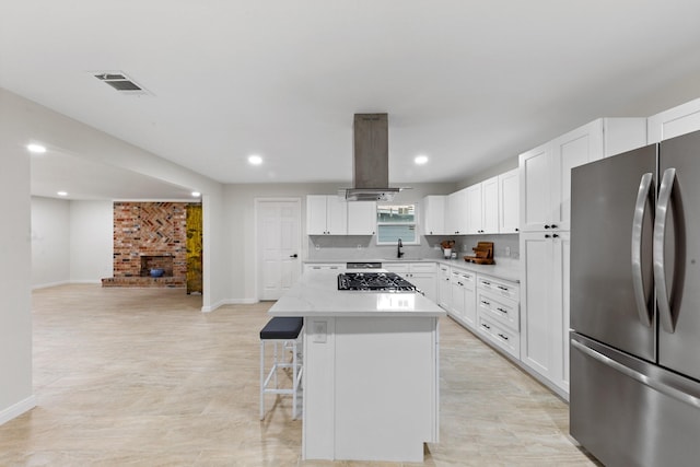 3915 Southmore Cir, Houston, TX 77004 - kitchen with stainless steel appliances, island exhaust hood, a center island, a breakfast bar area, and white cabinetry