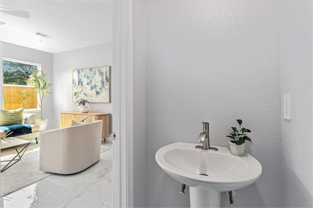 9311 Noel St, Houston, TX 77033 - bathroom with marble look tile flooring, ceiling fan, and a textured wall