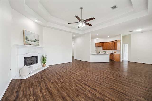 25207 Oak Star Dr, Spring, TX 77389 - unfurnished living room with a raised ceiling, dark wood-style floors, ceiling fan, a fireplace with raised hearth, and recessed lighting