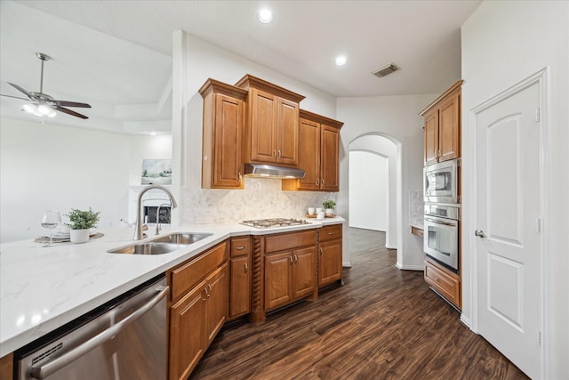 25207 Oak Star Dr, Spring, TX 77389 - kitchen featuring arched walkways, a ceiling fan, appliances with stainless steel finishes, dark wood-style floors, and tasteful backsplash