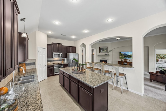 12314 Meadow Blossom Ln, Cypress, TX 77433 - kitchen with stainless steel appliances, dark brown cabinetry, a center island, light stone countertops, and backsplash