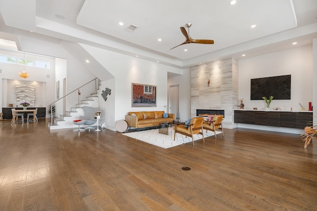 18 Pronghorn Pl, The Woodlands, TX 77389 - living room featuring a tray ceiling, a towering ceiling, stairs, a fireplace, and wood finished floors