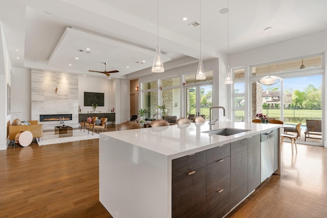 18 Pronghorn Pl, The Woodlands, TX 77389 - kitchen featuring stainless steel dishwasher, a premium fireplace, modern cabinets, an island with sink, and light countertops