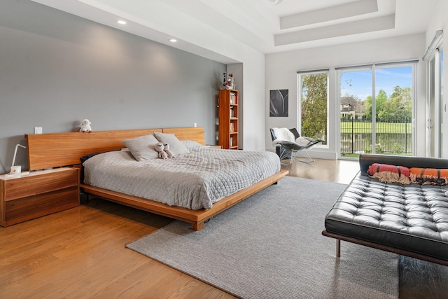 18 Pronghorn Pl, The Woodlands, TX 77389 - bedroom with access to outside, wood finished floors, a tray ceiling, and recessed lighting