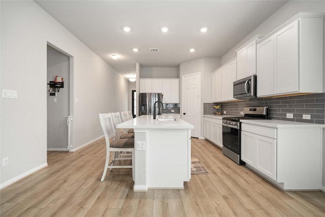 13402 Rain Lily, Texas City, TX 77568 - kitchen with stainless steel appliances, tasteful backsplash, a center island with sink, recessed lighting, and light wood-style flooring