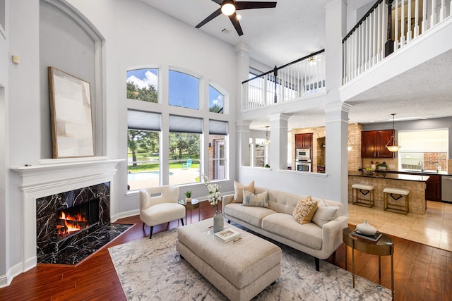 427 Crestwater Trl, Houston, TX 77082 - living room with wood-type flooring, a ceiling fan, a high end fireplace, ornate columns, and a high ceiling