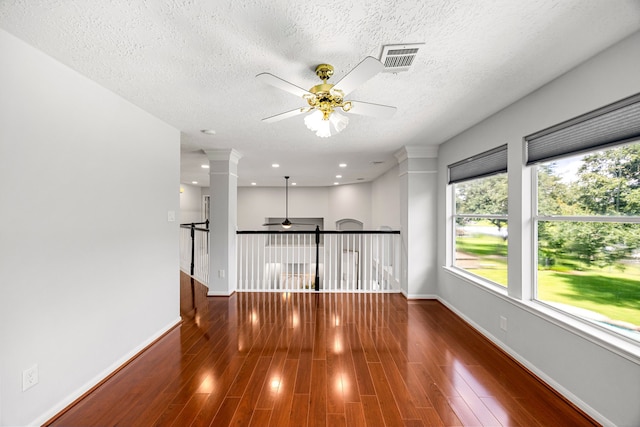 427 Crestwater Trl, Houston, TX 77082 - empty room with ceiling fan, wood finished floors, a textured ceiling, decorative columns, and recessed lighting