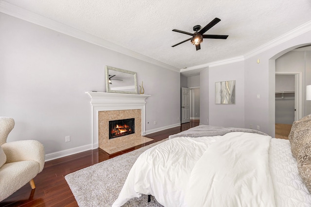 427 Crestwater Trl, Houston, TX 77082 - bedroom featuring arched walkways, dark wood-style floors, crown molding, a high end fireplace, and a textured ceiling