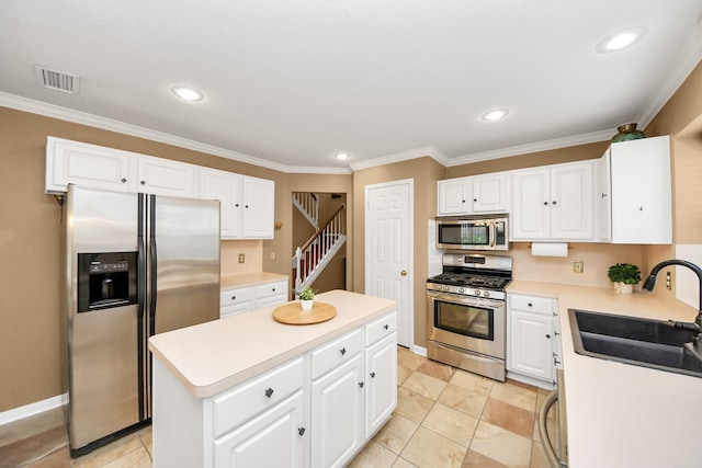 20527 Apache Lake Dr, Katy, TX 77449 - kitchen featuring appliances with stainless steel finishes, a kitchen island, crown molding, light countertops, and white cabinets