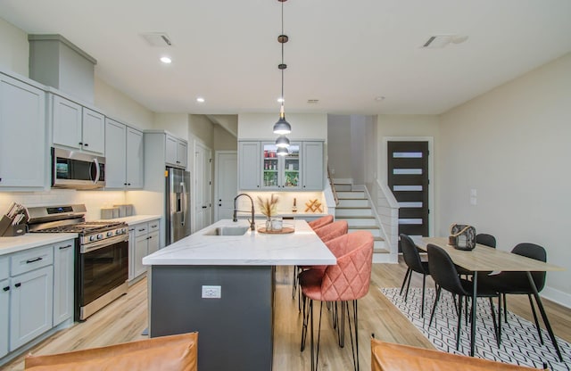 4612 Oats St, Houston, TX 77020 - kitchen with stainless steel appliances, a kitchen island with sink, light wood-type flooring, backsplash, and recessed lighting