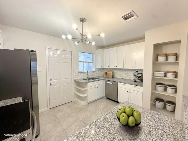 11026 Catamore St, Houston, TX 77076 - kitchen with stainless steel appliances, light tile patterned floors, white cabinets, a chandelier, and decorative backsplash