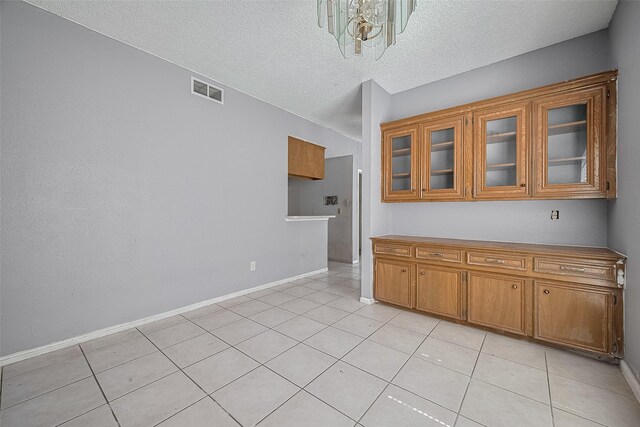 11280 Braes Forest Dr Unit 105, Houston, TX 77071 - kitchen with brown cabinets, light tile patterned floors, glass insert cabinets, and a textured ceiling