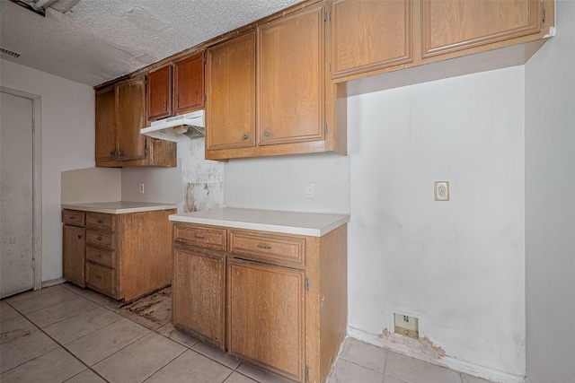 11280 Braes Forest Dr Unit 105, Houston, TX 77071 - kitchen featuring under cabinet range hood, light tile patterned floors, light countertops, and brown cabinets