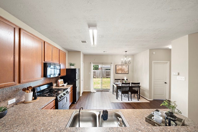6707 Enchanted Crest Dr, Katy, TX 77449 - kitchen with black appliances, dark wood-type flooring, a chandelier, light countertops, and decorative backsplash
