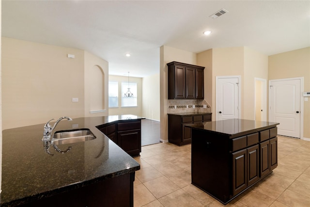 38 Tallgrass Way, Spring, TX 77389 - kitchen featuring a center island, light tile patterned floors, dark stone counters, backsplash, and dark brown cabinets