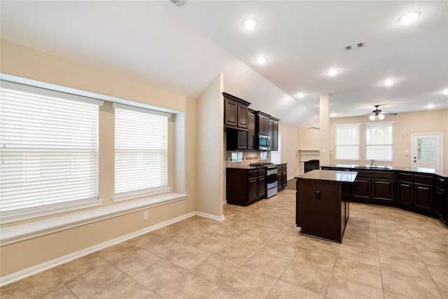 38 Tallgrass Way, Spring, TX 77389 - kitchen featuring appliances with stainless steel finishes, a fireplace, ceiling fan, a kitchen island, and dark brown cabinetry