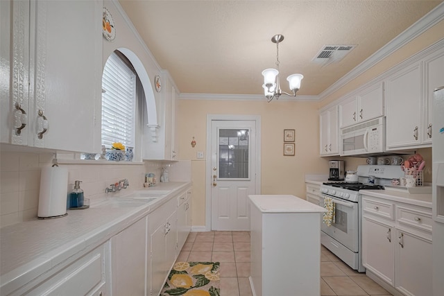 7833 Narcissus St, Houston, TX 77012 - kitchen with white appliances, white cabinetry, a chandelier, backsplash, and light countertops
