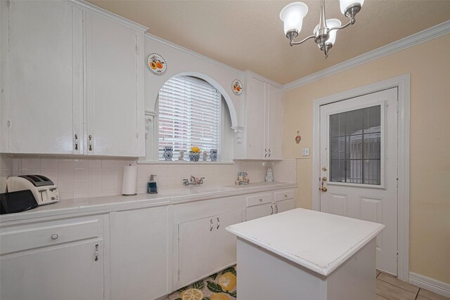 7833 Narcissus St, Houston, TX 77012 - kitchen with a chandelier, decorative backsplash, crown molding, white cabinets, and tile counters
