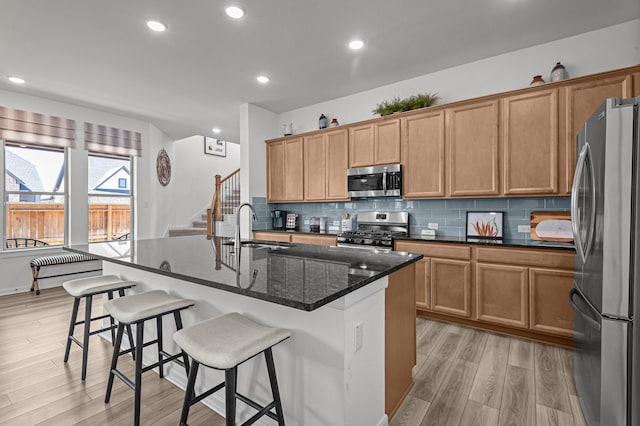 10502 William Park Dr, Missouri City, TX 77459 - kitchen with appliances with stainless steel finishes, light wood-style floors, tasteful backsplash, a kitchen bar, and recessed lighting