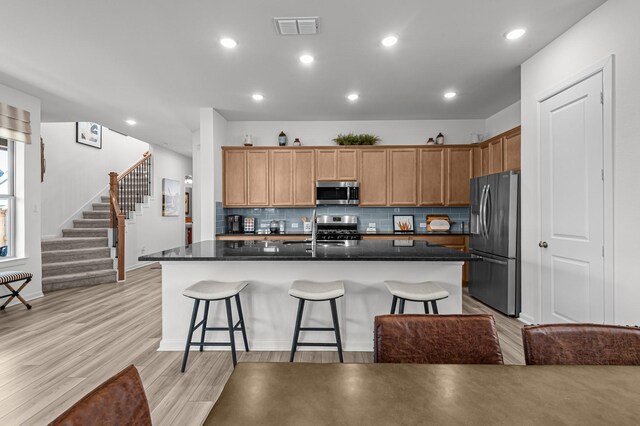 10502 William Park Dr, Missouri City, TX 77459 - kitchen featuring stainless steel appliances, dark countertops, tasteful backsplash, a breakfast bar, and a center island with sink