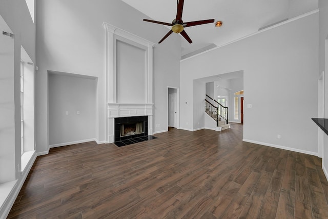 13810 Lakewood Crossing Blvd, Houston, TX 77070 - unfurnished living room with a towering ceiling, a tile fireplace, ceiling fan, stairway, and dark wood-type flooring