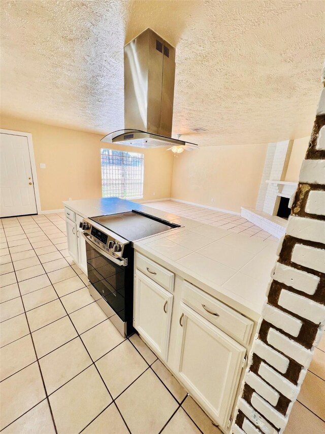 14634 Edenglen Dr, Houston, TX 77049 - kitchen featuring electric stove, island range hood, tile countertops, a textured ceiling, and light tile patterned floors