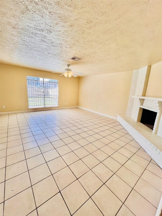 14634 Edenglen Dr, Houston, TX 77049 - unfurnished living room with ceiling fan, a brick fireplace, light tile patterned floors, and a textured ceiling