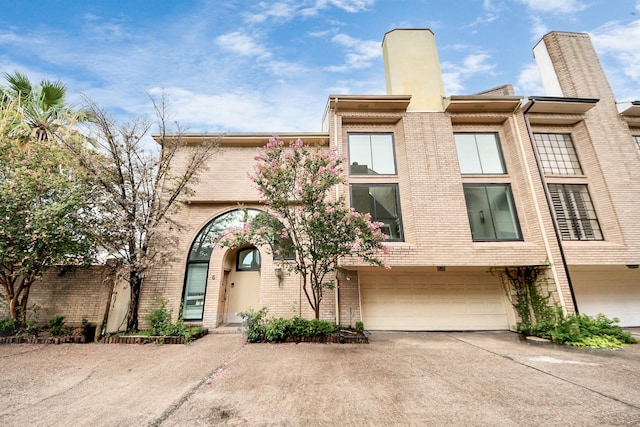 1425 Nantucket Dr Unit G, Houston, TX 77057 - view of front of home featuring driveway, brick siding, an attached garage, and a chimney