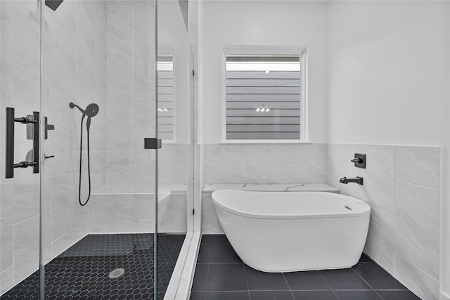 4517 Teton St, Houston, TX 77051 - bathroom with a freestanding tub, a shower stall, tile walls, tile patterned flooring, and a wainscoted wall