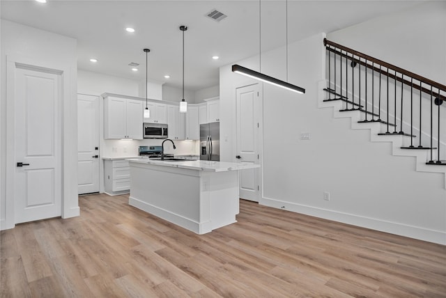 4517 Teton St, Houston, TX 77051 - kitchen with appliances with stainless steel finishes, light wood-type flooring, white cabinets, a center island with sink, and recessed lighting