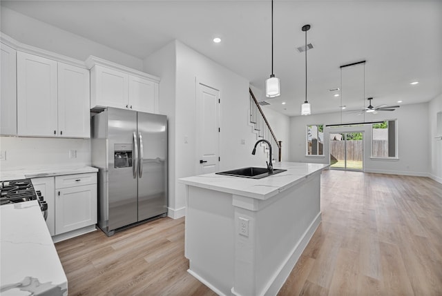4517 Teton St, Houston, TX 77051 - kitchen featuring stainless steel fridge, light wood-style floors, white cabinets, ceiling fan, and light stone countertops