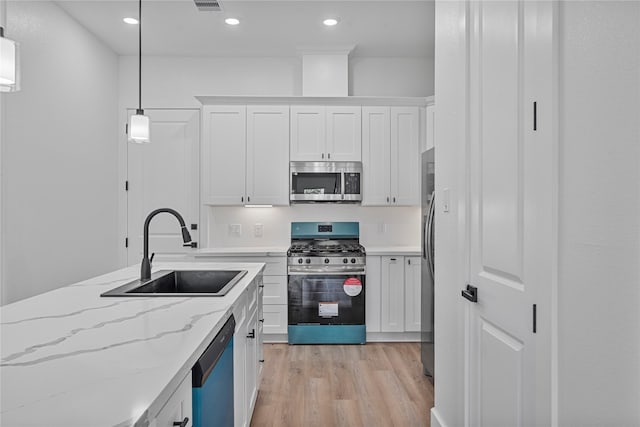 4517 Teton St, Houston, TX 77051 - kitchen featuring stainless steel appliances, white cabinets, light wood-style floors, hanging light fixtures, and recessed lighting