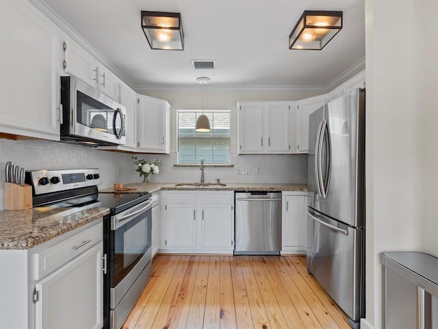 1409 Blair St, Houston, TX 77008 - kitchen with stainless steel appliances, white cabinetry, backsplash, light stone counters, and light wood-style flooring