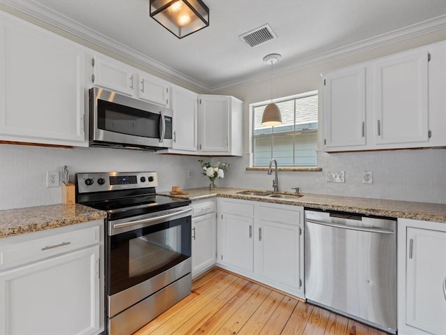 1409 Blair St, Houston, TX 77008 - kitchen featuring appliances with stainless steel finishes, white cabinets, crown molding, and light wood finished floors