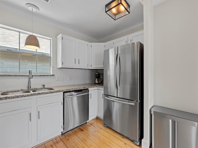 1409 Blair St, Houston, TX 77008 - kitchen with appliances with stainless steel finishes, white cabinets, ornamental molding, light wood-type flooring, and hanging light fixtures