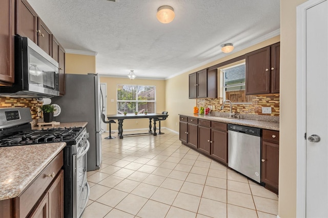 15026 Sunset Creek Dr, Humble, TX 77396 - kitchen featuring stainless steel appliances, crown molding, decorative backsplash, light tile patterned flooring, and dark brown cabinets