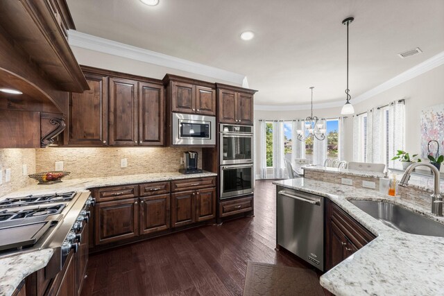 6051 Longmire Trl, Conroe, TX 77304 - kitchen with appliances with stainless steel finishes, crown molding, a chandelier, dark brown cabinets, and tasteful backsplash
