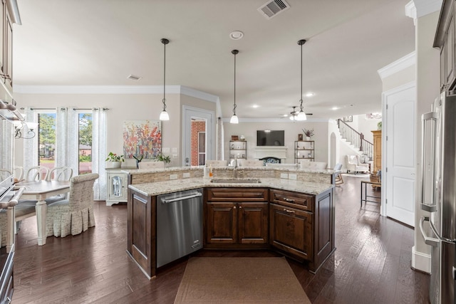 6051 Longmire Trl, Conroe, TX 77304 - kitchen with stainless steel appliances, a ceiling fan, open floor plan, a fireplace, and ornamental molding