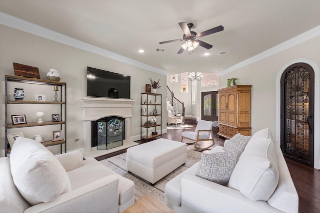 6051 Longmire Trl, Conroe, TX 77304 - living room with stairs, wood finished floors, arched walkways, a fireplace with raised hearth, and ornamental molding