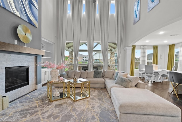 27915 Round Moon Ln, Katy, TX 77494 - living area with a high ceiling, a fireplace, arched walkways, decorative columns, and wood finished floors