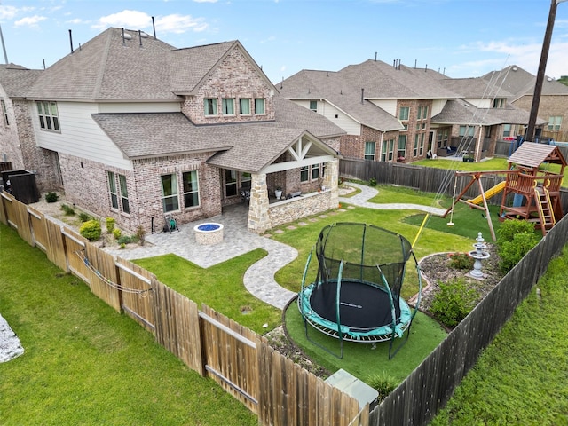 27915 Round Moon Ln, Katy, TX 77494 - back of property featuring a trampoline, brick siding, a patio, roof with shingles, and a residential view