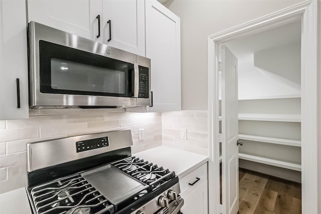 2353 Hoskins Dr, Houston, TX 77080 - kitchen featuring appliances with stainless steel finishes, white cabinets, wood finished floors, light countertops, and tasteful backsplash