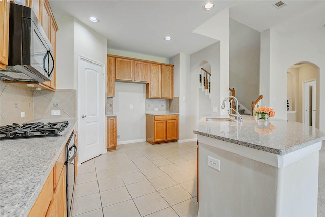 20311 Towering Cypress Dr, Cypress, TX 77433 - kitchen with black appliances, arched walkways, backsplash, light stone countertops, and light tile patterned floors