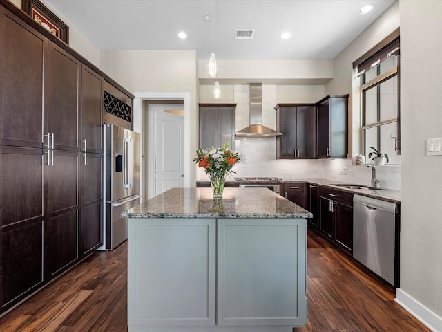 1437 Wagner St, Houston, TX 77007 - kitchen featuring stainless steel appliances, wall chimney exhaust hood, dark wood-style flooring, light stone countertops, and a kitchen island