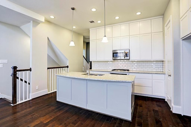 11005 Acorn Falls Dr, Houston, TX 77043 - kitchen featuring stainless steel microwave, dark wood-style floors, decorative backsplash, light stone countertops, and recessed lighting
