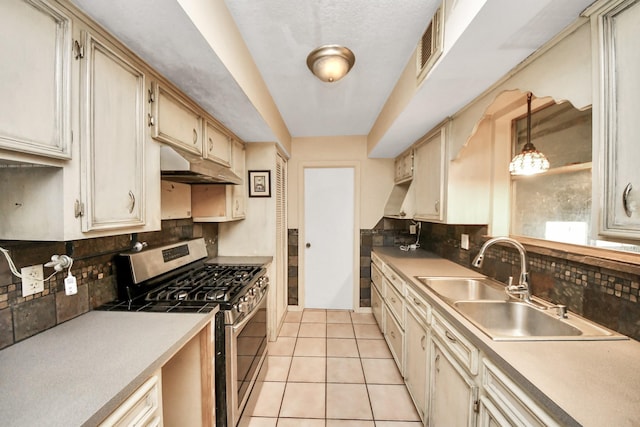 30718 N Cripple Creek Dr, Magnolia, TX 77354 - kitchen with stainless steel gas range oven, under cabinet range hood, tasteful backsplash, light tile patterned flooring, and light countertops