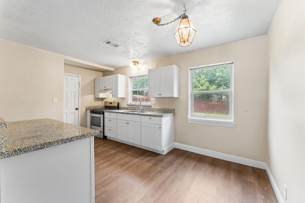 14106 Burtcliff St, Houston, TX 77060 - kitchen featuring stainless steel gas stove, light wood-style flooring, white cabinetry, a textured ceiling, and pendant lighting