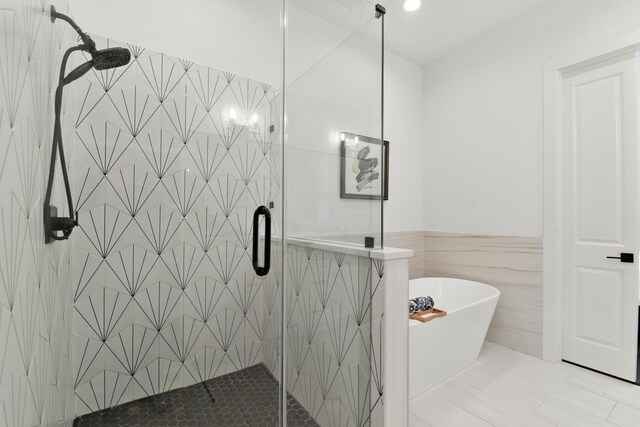 3913 Hare St, Houston, TX 77020 - bathroom featuring a shower stall, a soaking tub, tile walls, and wainscoting