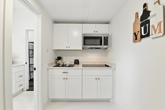 3913 Hare St, Houston, TX 77020 - kitchen featuring stainless steel microwave, white cabinetry, black electric stovetop, light countertops, and light tile patterned floors